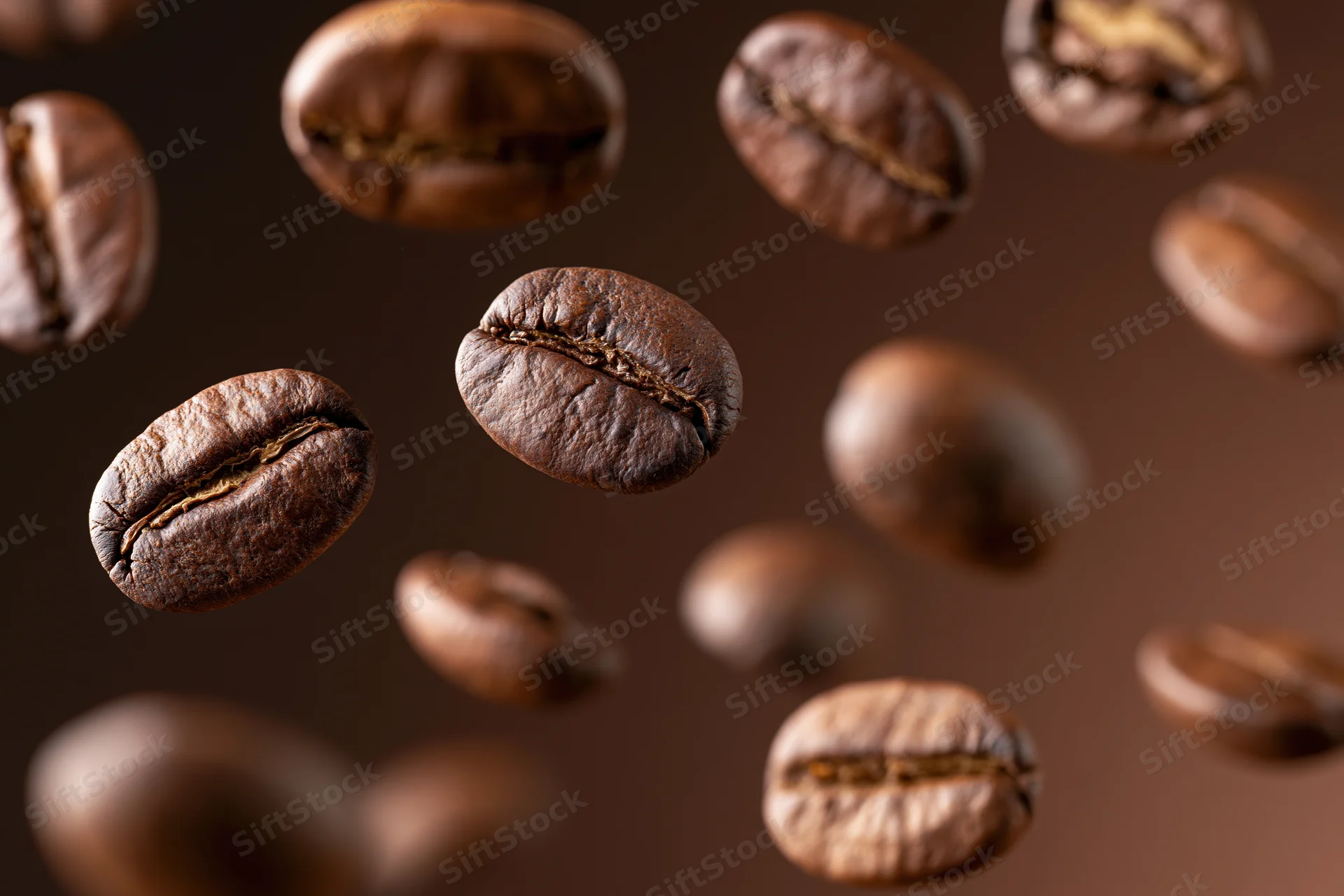 Roasted coffee beans floating midair against a dark brown background