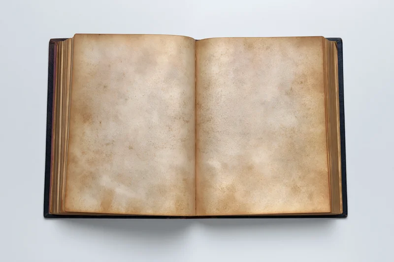 Open vintage hardcover book with blank aged pages on white surface
