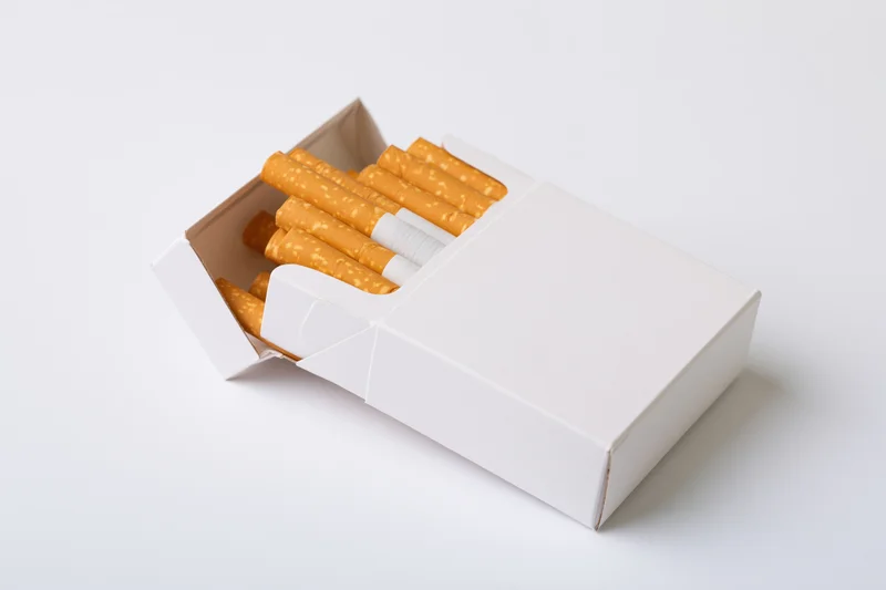 Open white cigarette pack with cigarettes visible on plain background