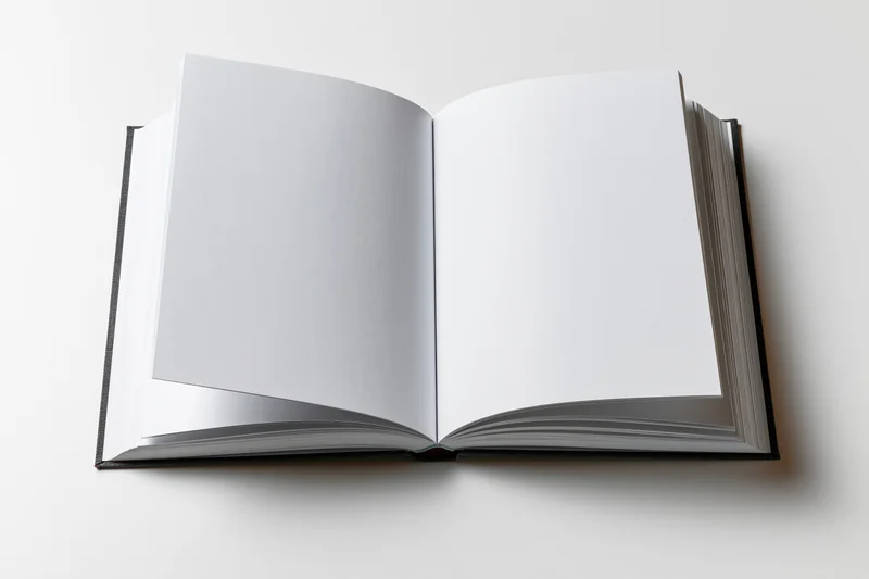 Open hardcover book lying flat with blank white pages on white surface