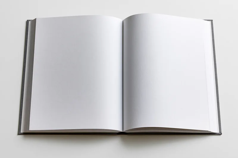 Open hardcover book with blank white pages lying flat on a white surface