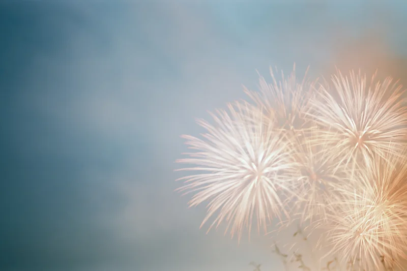 Fireworks bursting softly in the hazy night sky