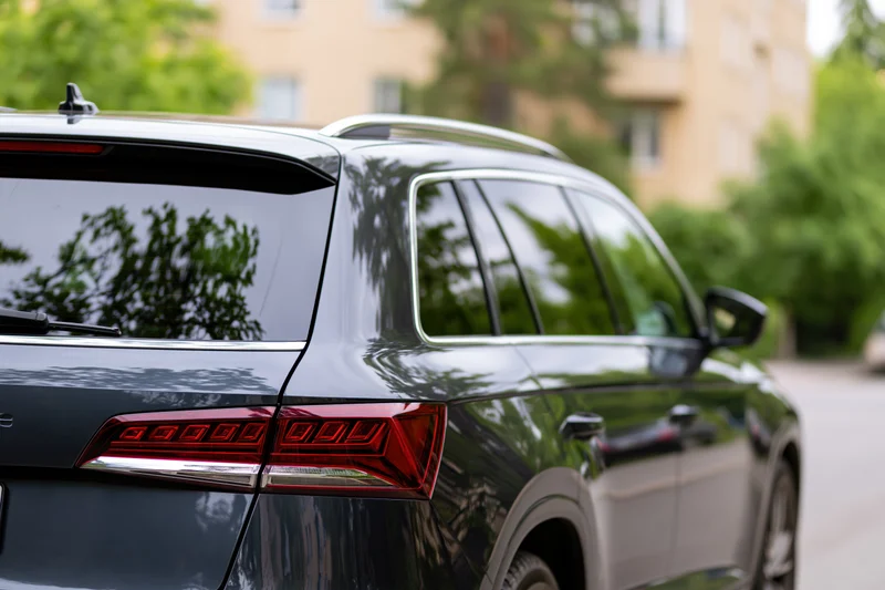 Rear closeup of a dark black suv parked on a residential street with trees and buildings in the background