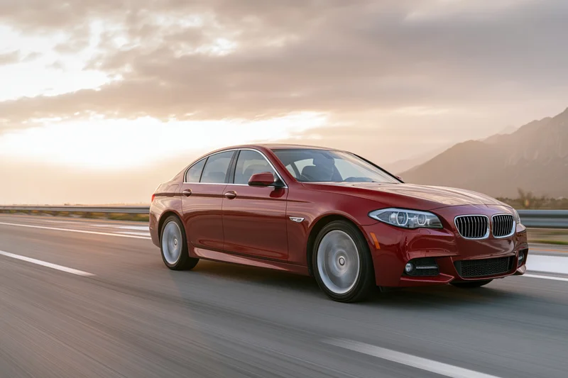 Red luxury sedan driving on open highway at sunset