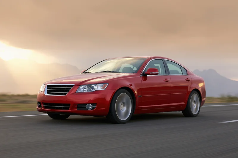 Red luxury sedan driving on open highway at sunset