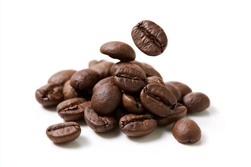 Roasted coffee beans falling and landing onto a small pile on white background