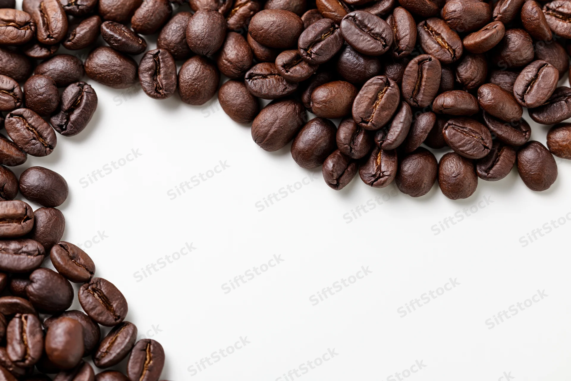 Roasted coffee beans scattered along the top and left edges on a white surface, leaving copyspace in the center