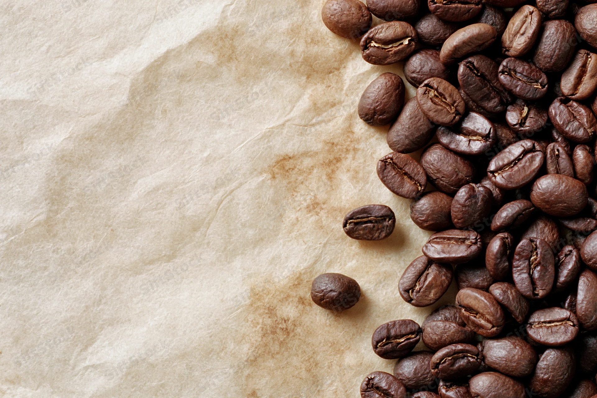 Roasted coffee beans scattered along the right edge of crumpled parchment paper