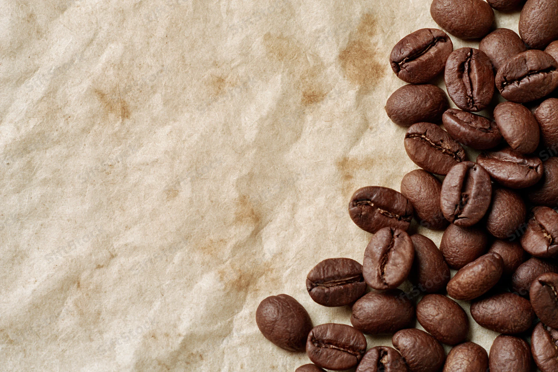Roasted coffee beans scattered along the right edge of crumpled parchment paper