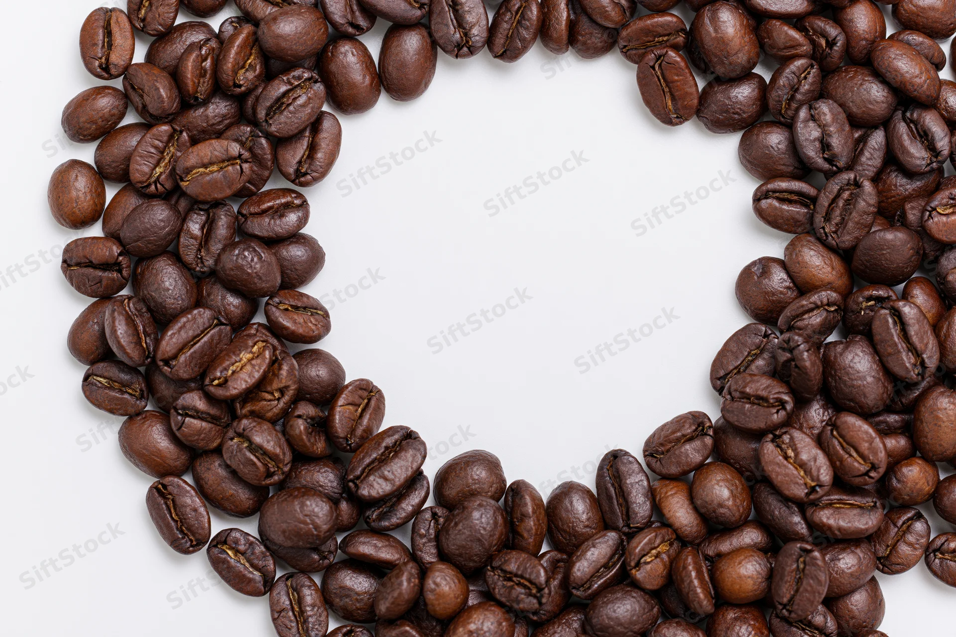 Roasted coffee beans arranged in a curved border on a white background