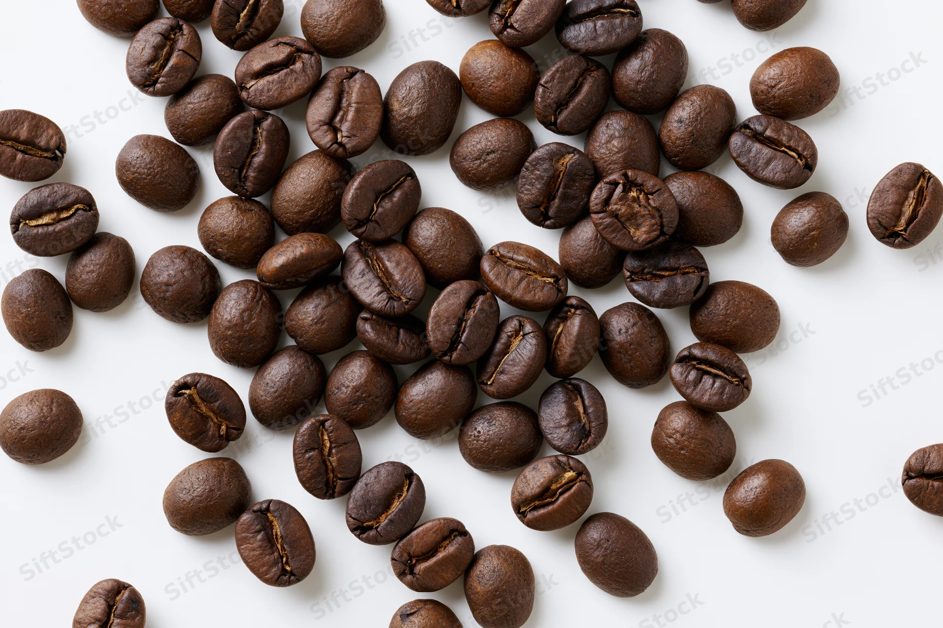 Roasted coffee beans scattered across a flat white surface