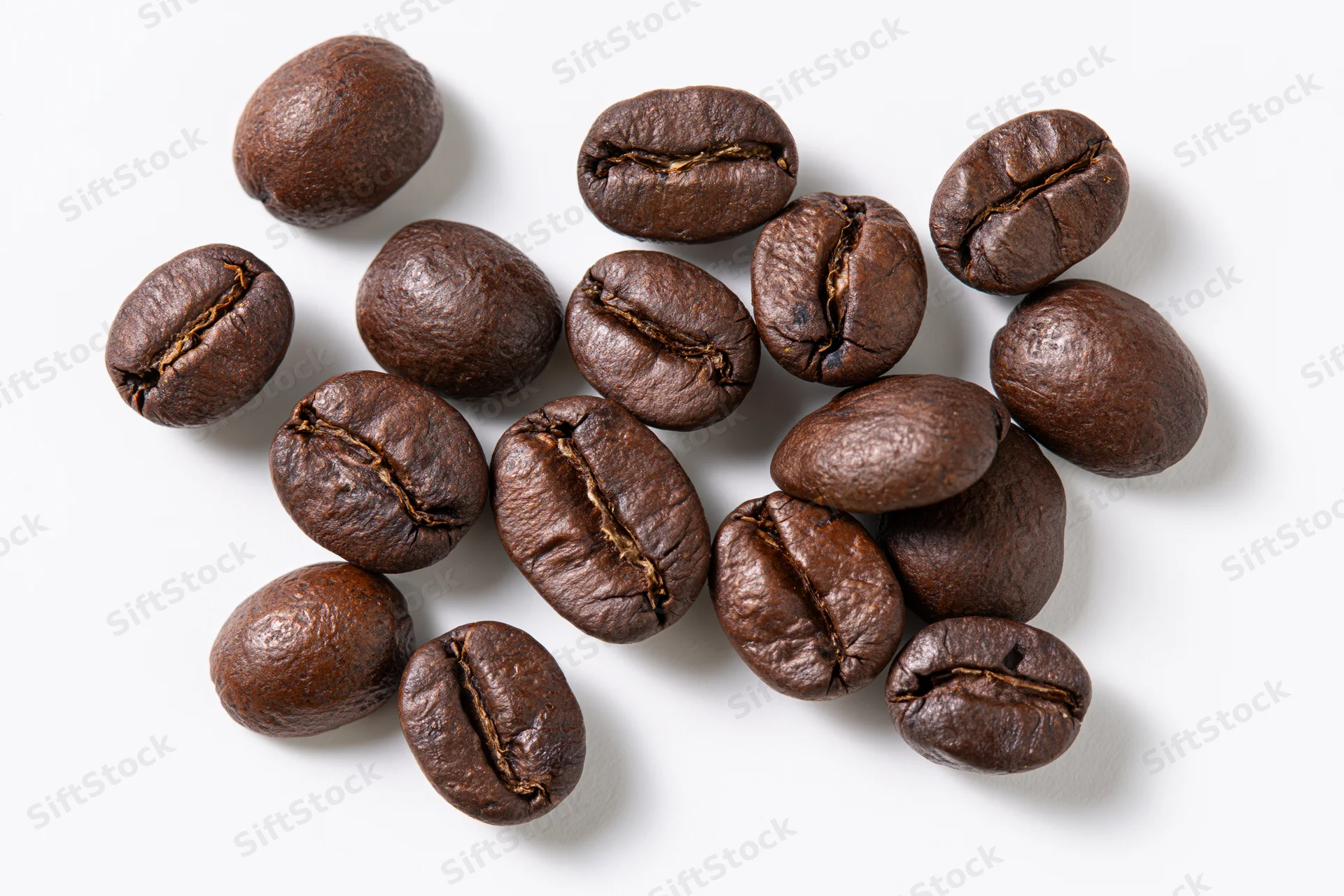 Roasted coffee beans scattered on a white background