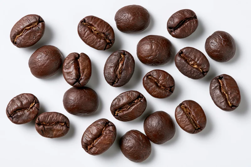 Roasted coffee beans scattered on a white background