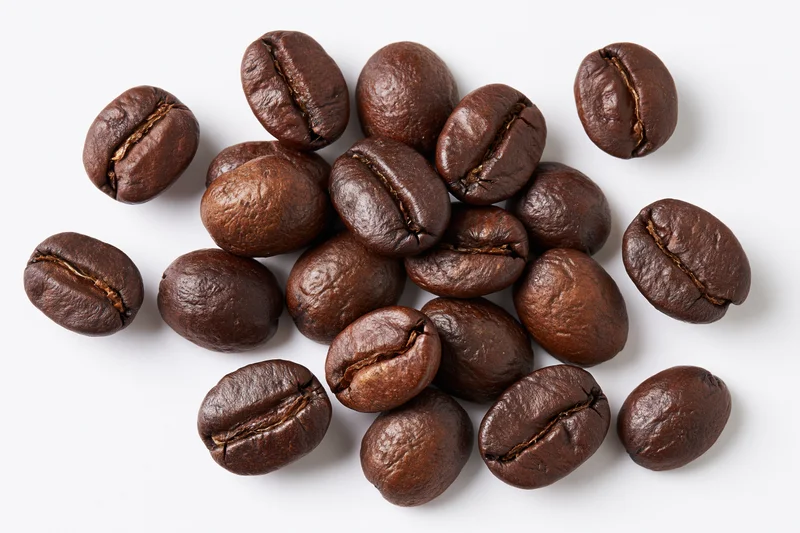 Roasted coffee beans scattered on a white background