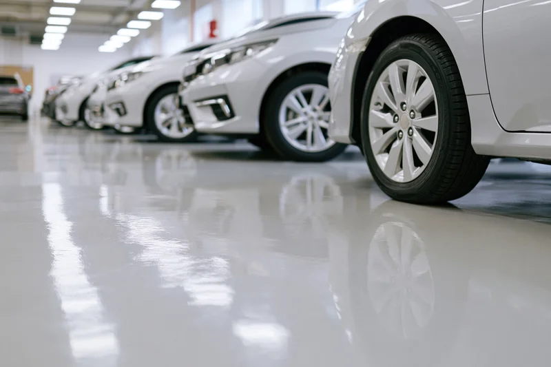 Row of white cars parked in a showroom with glossy floor reflections