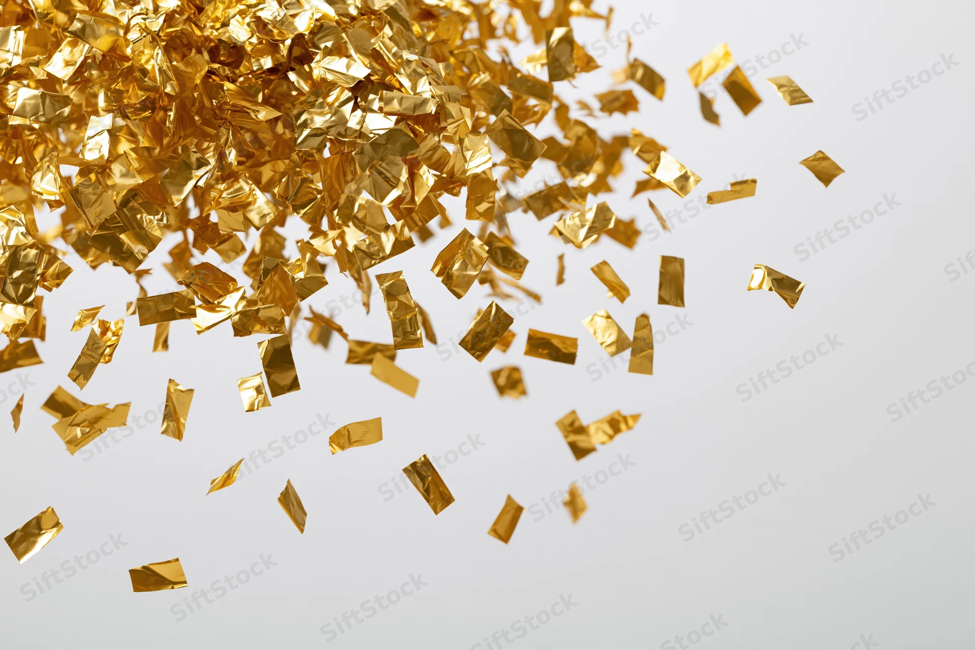 Gold foil confetti falling and scattering across a white background with copyspace on the right