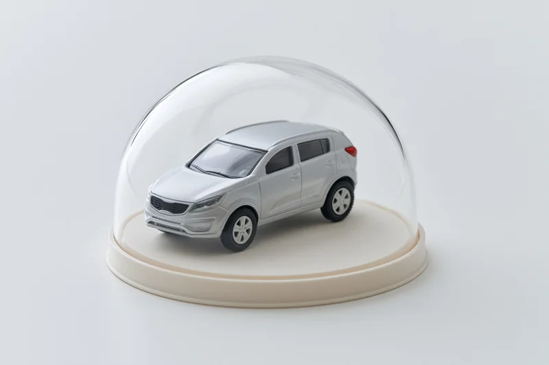 Silver toy suv model under clear glass dome on white base