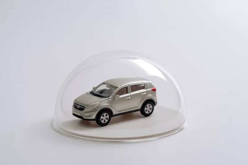 Silver toy suv model under a clear glass dome on white background