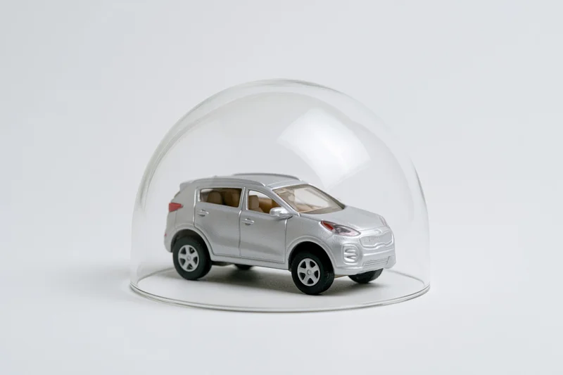 Silver toy suv model under a clear glass dome on white background