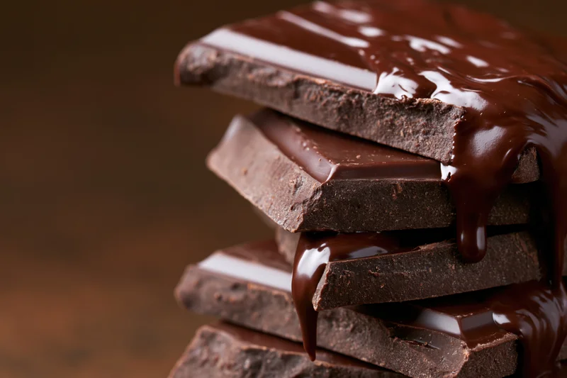 Stacked dark chocolate squares with melted chocolate dripping down the sides