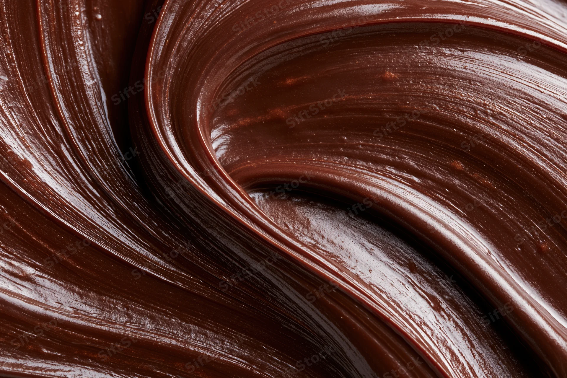 Thick dark chocolate ganache in smooth flowing swirls filling the frame