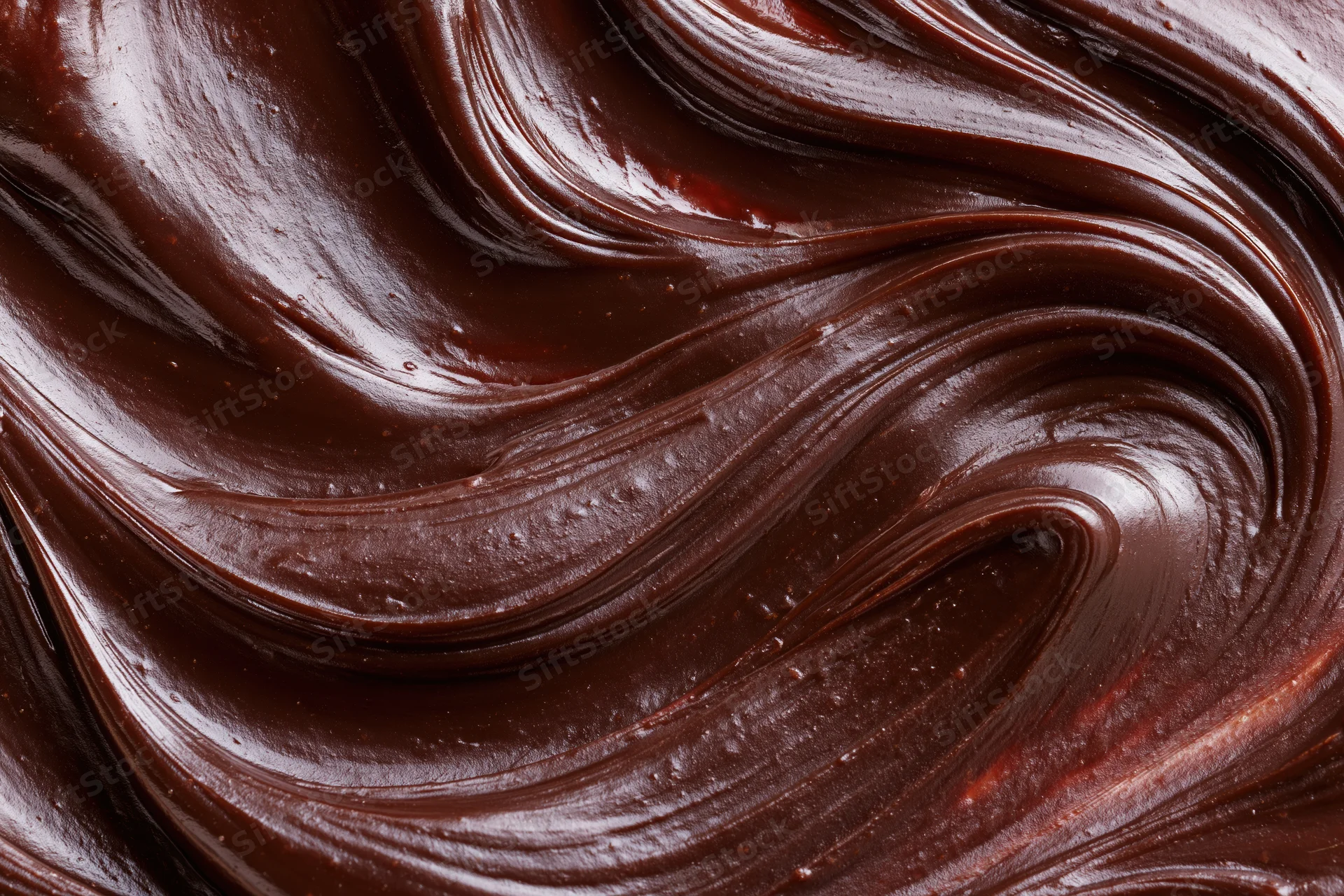 Thick dark chocolate ganache in smooth flowing swirls closeup