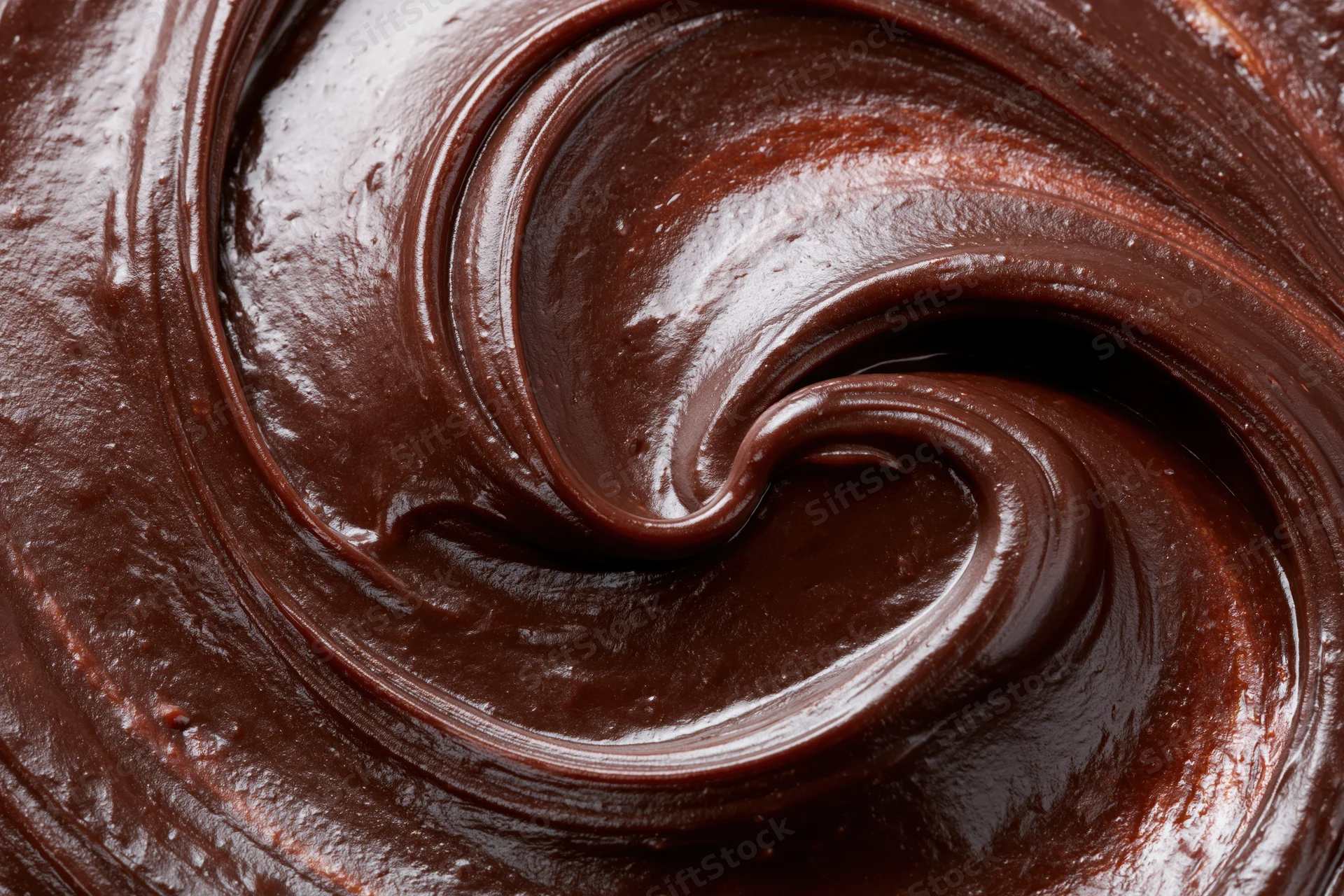 Thick dark chocolate ganache in smooth flowing swirls closeup