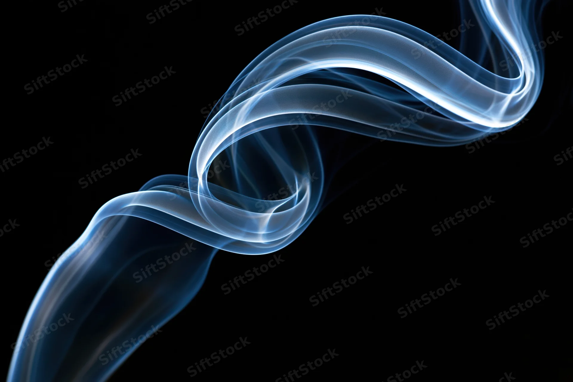Thin wisp of incense smoke curling into a looping swirl against black background