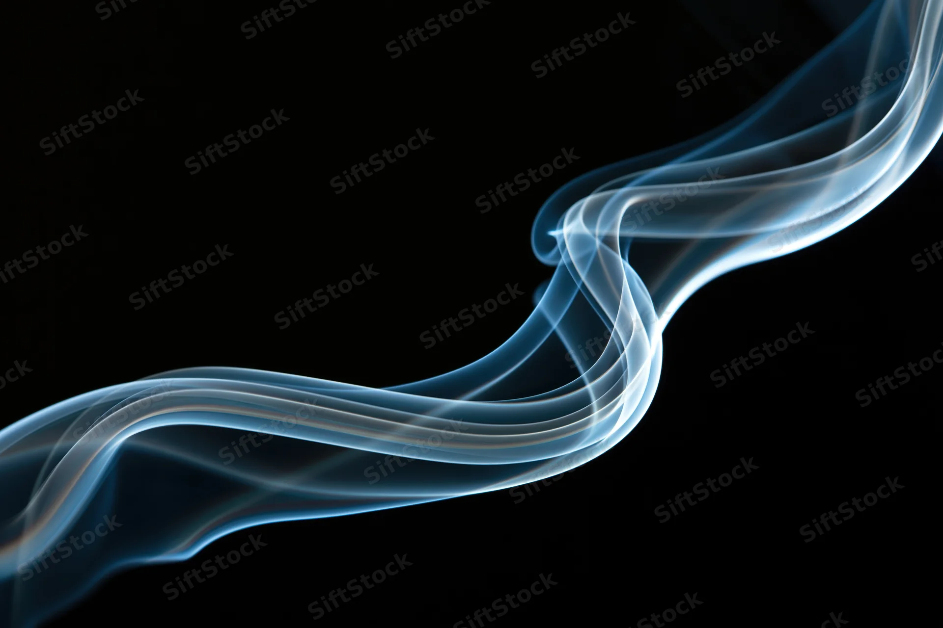 Thin wisp of incense smoke curling into a looping swirl against black background