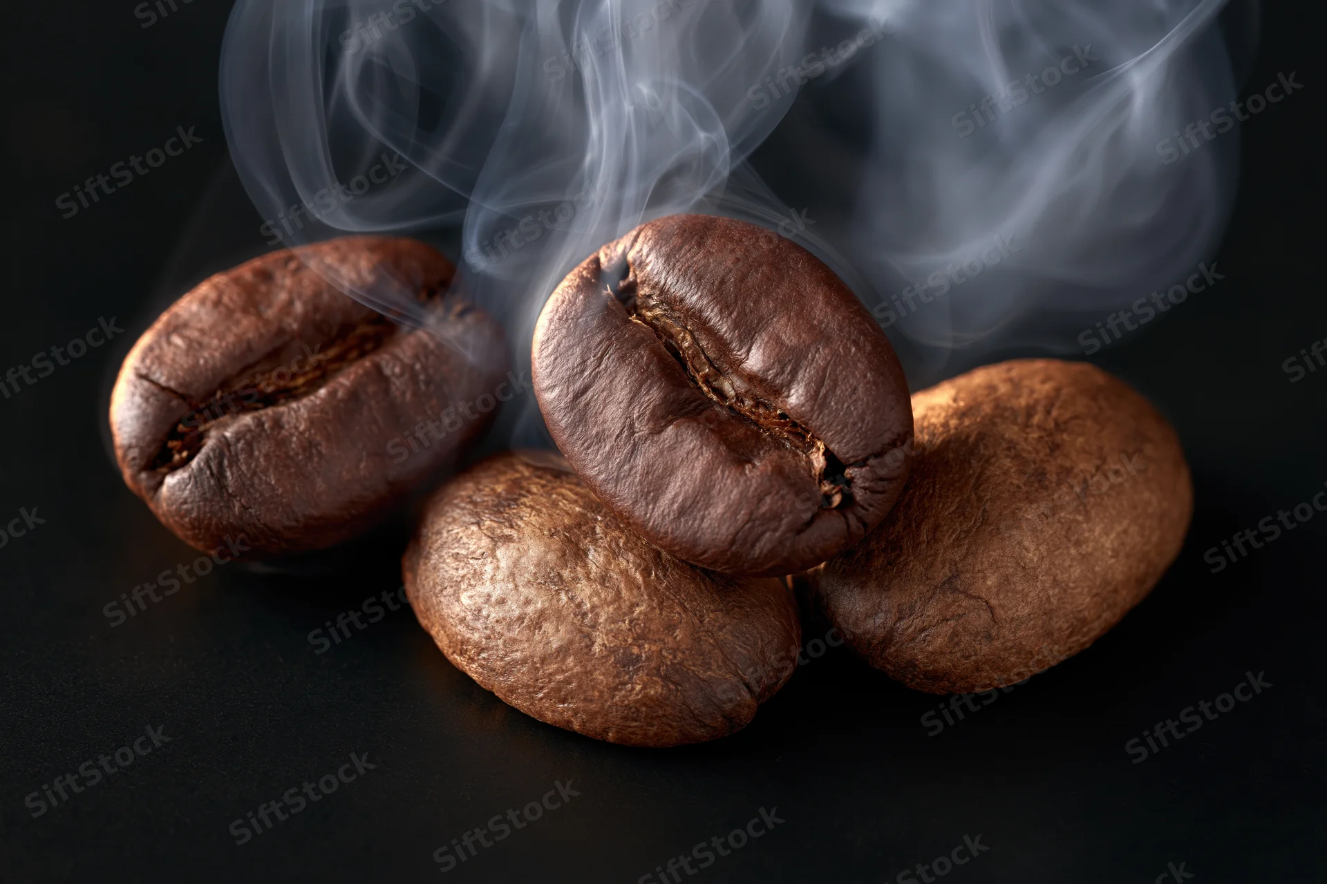 Roasted coffee beans emitting steam on a dark surface