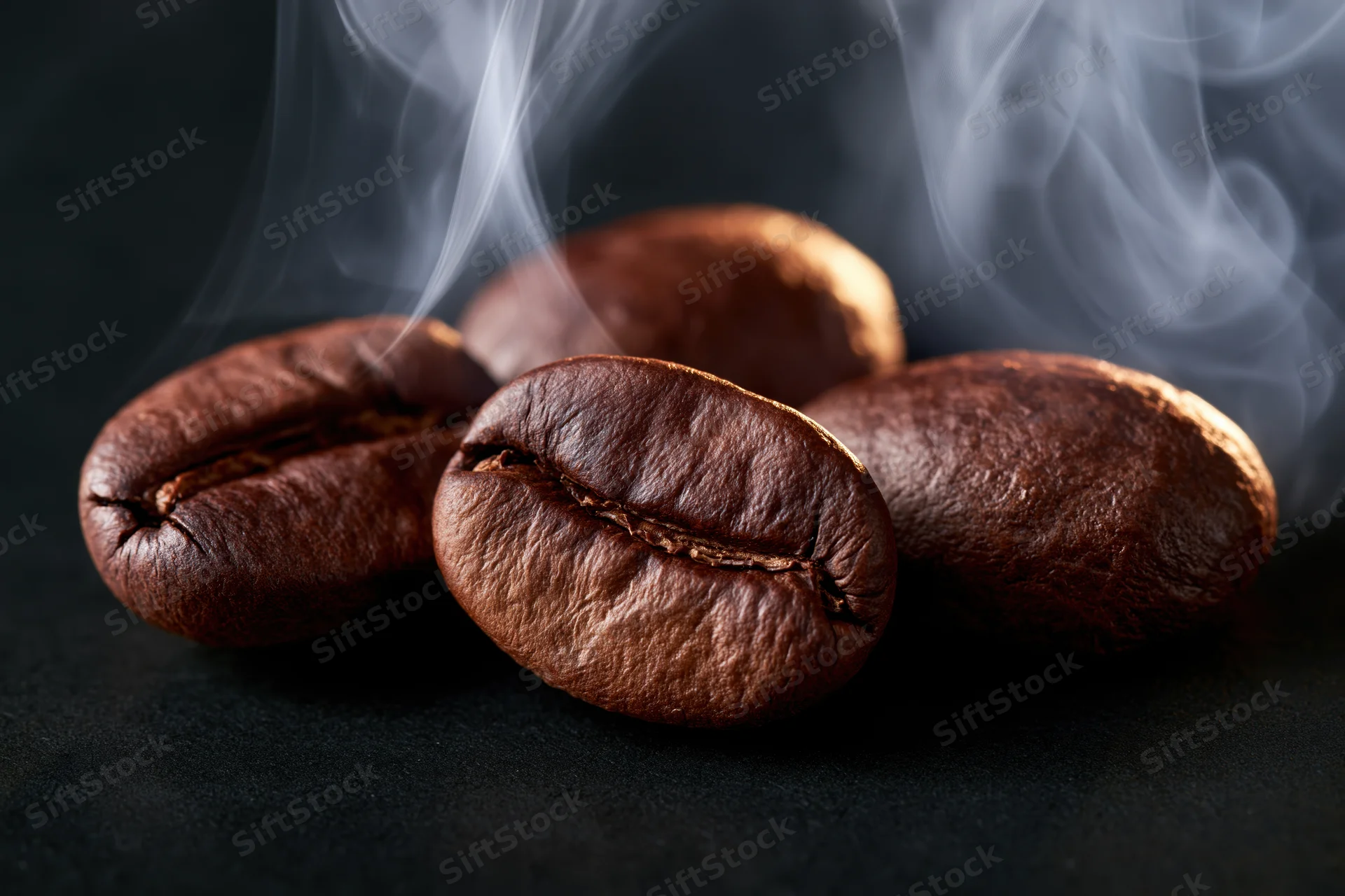 Roasted coffee beans with rising steam on dark surface