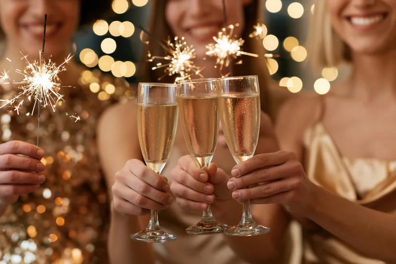 Three women toasting with champagne flutes and sparklers at a festive party