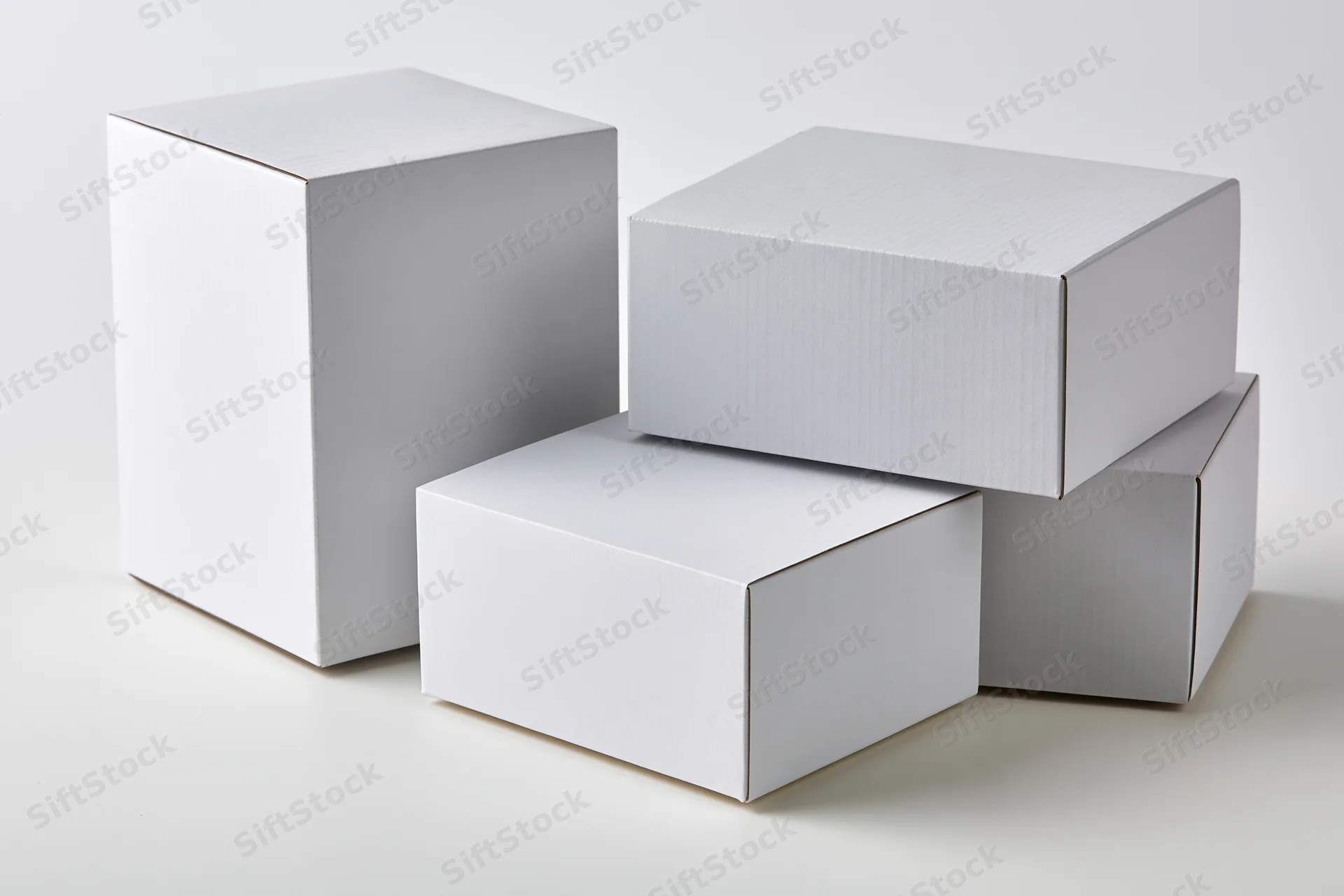 Plain white cardboard boxes arranged in a stack on a white surface