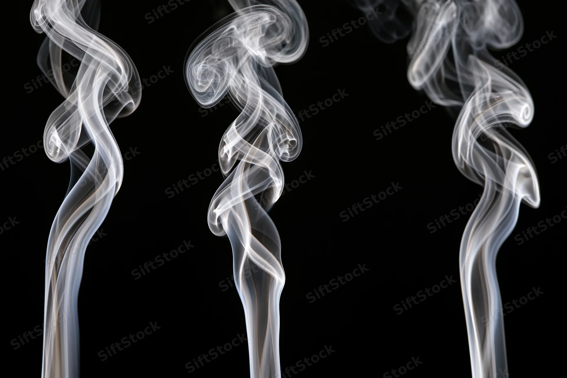 Three white smoke wisps rising and curling upward against a black background