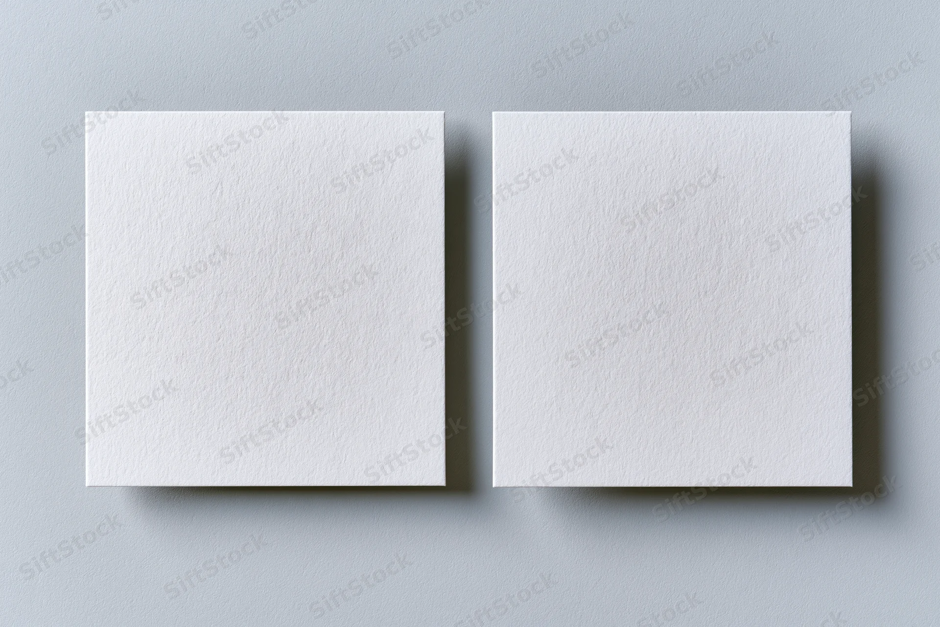 Two blank white textured business cards lying flat side by side on a gray surface