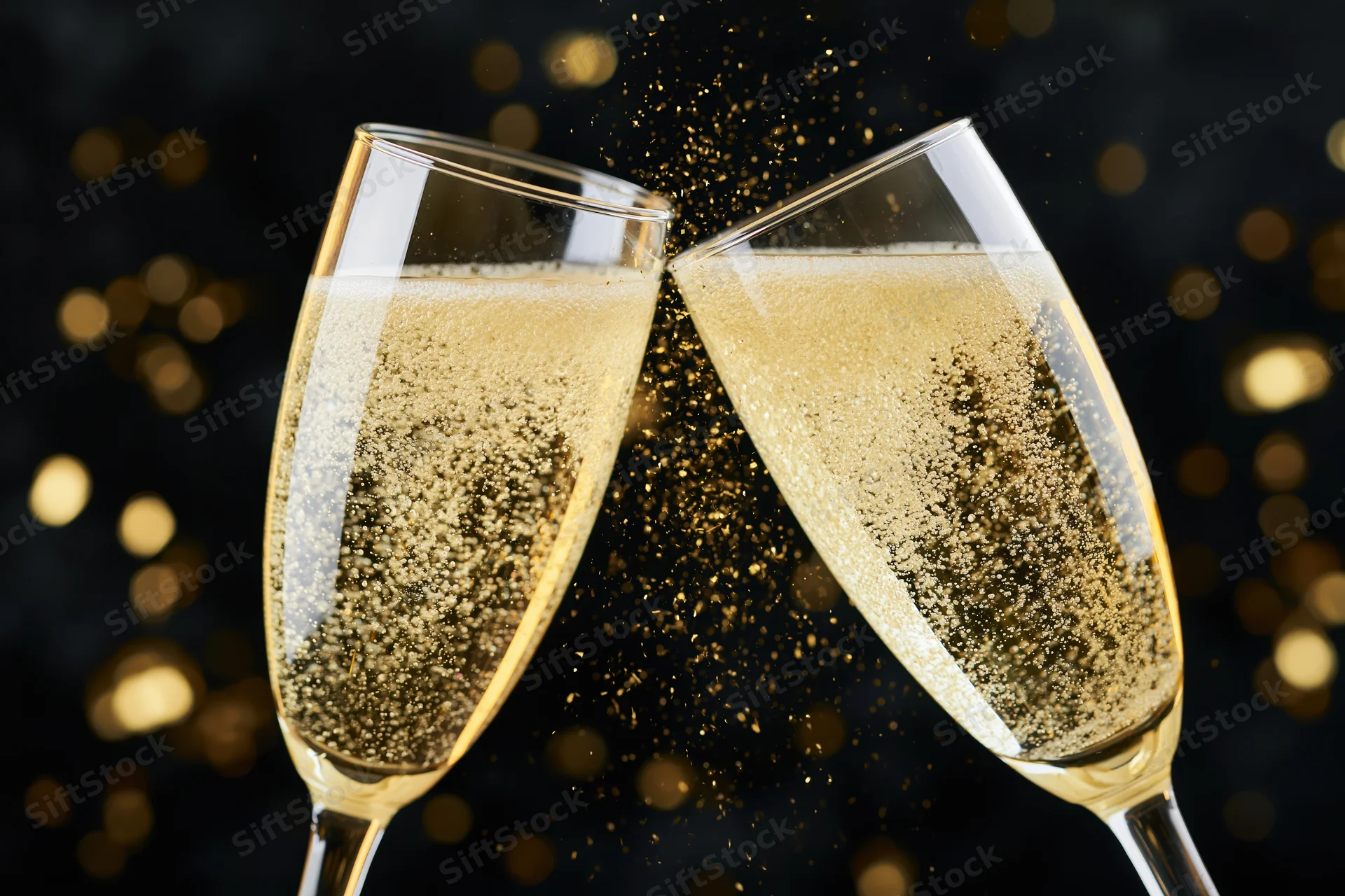 Two champagne flutes clinking together with golden bubbles and glitter against a dark bokeh background
