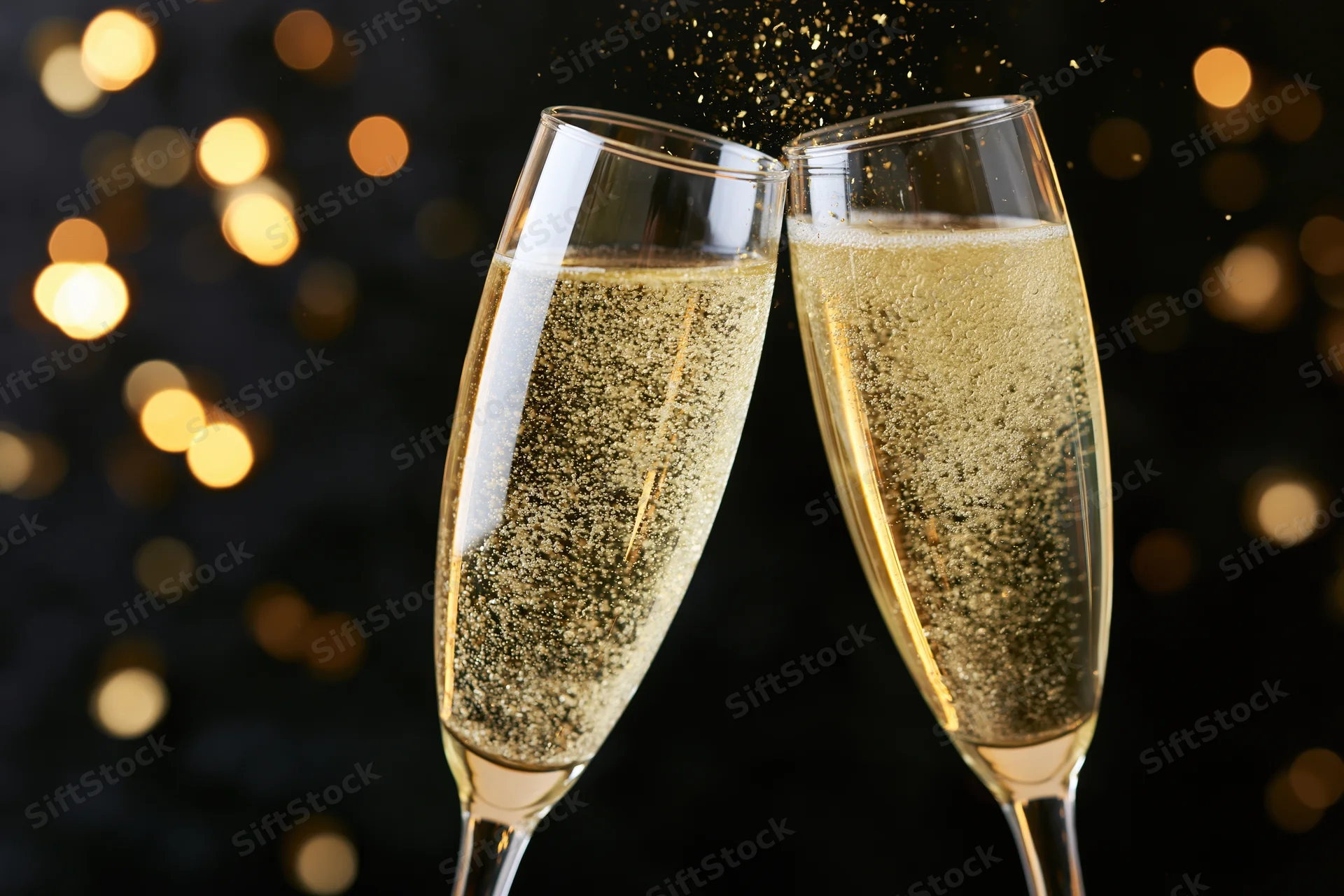 Two champagne flutes clinking together in a toast with golden bubbles and bokeh lights in the background