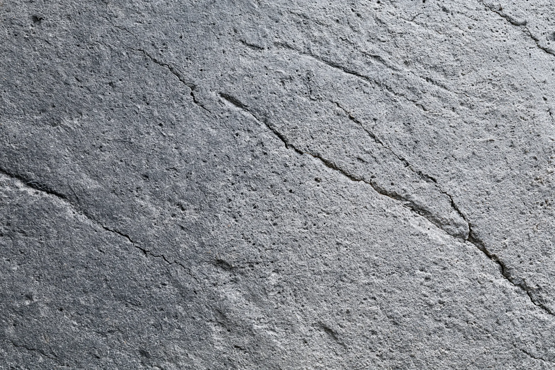 Weathered concrete surface with diagonal cracks and rough texture