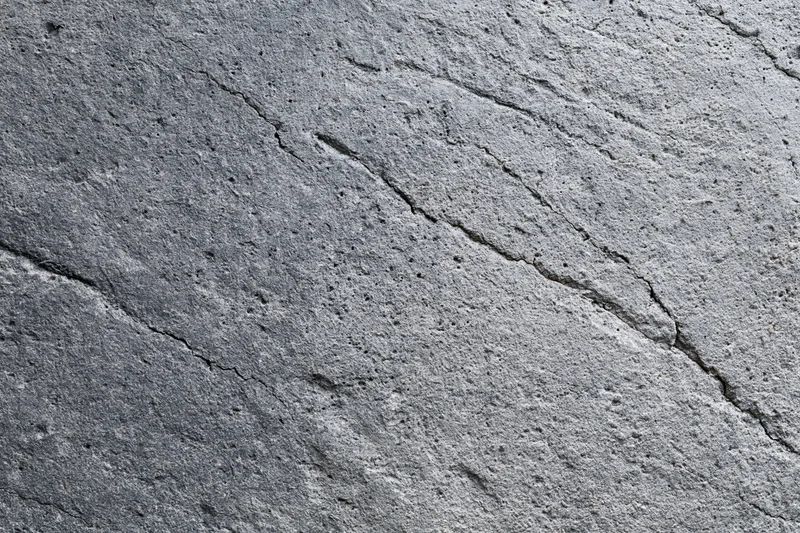 Weathered concrete surface with diagonal cracks and rough texture