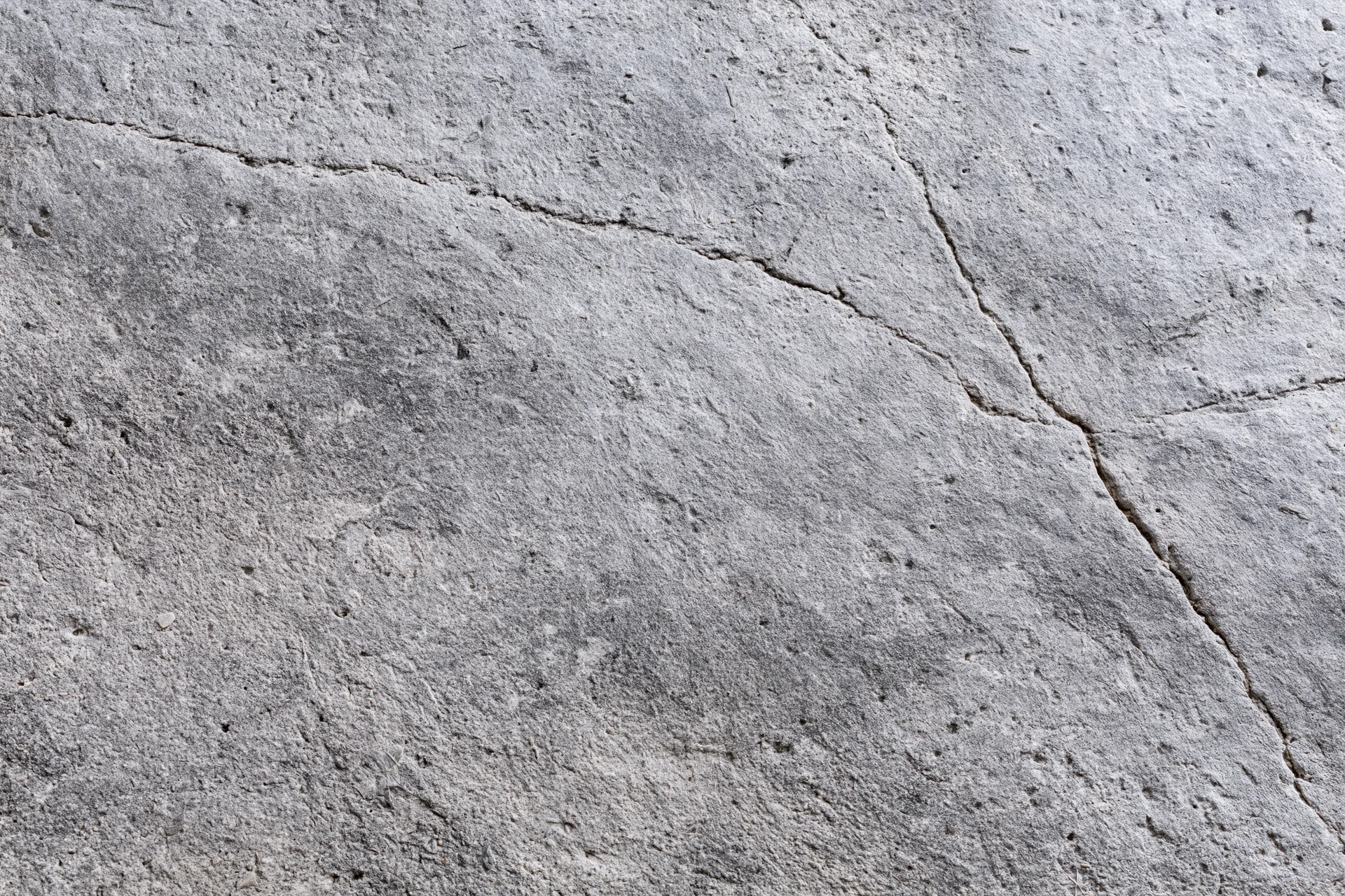 Weathered concrete surface with diagonal cracks and rough texture