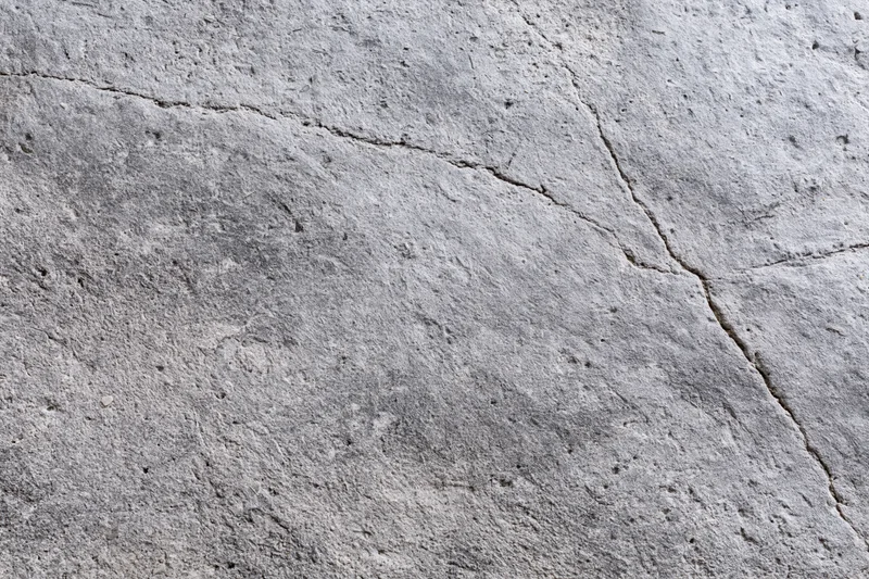 Weathered concrete surface with diagonal cracks and rough texture