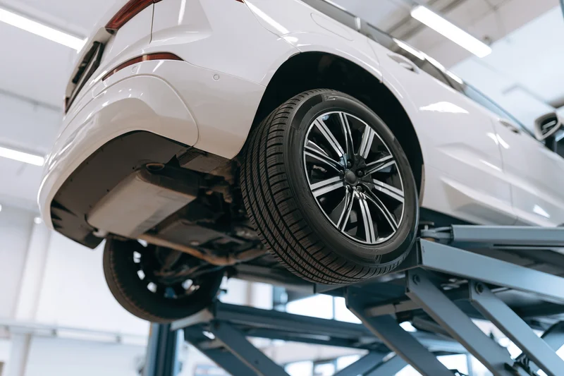 White suv raised on scissor lift in automotive service garage