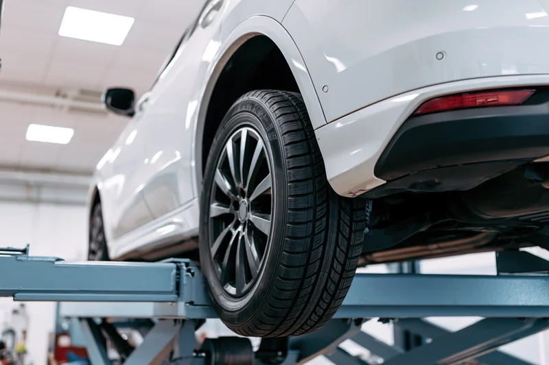 White suv raised on scissor lift in automotive service garage