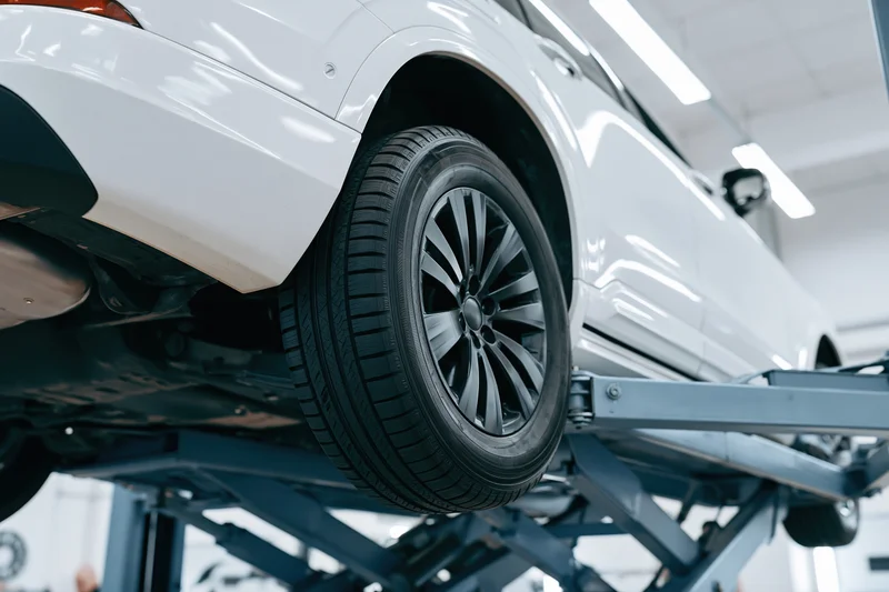 White suv raised on scissor lift in automotive service garage
