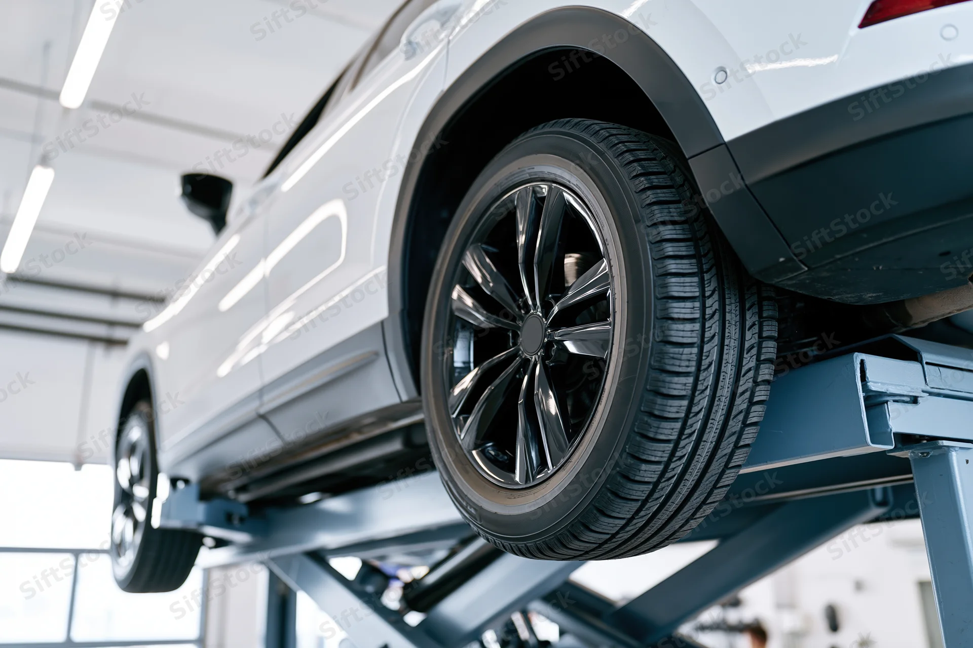 White suv raised on scissor lift in automotive service garage
