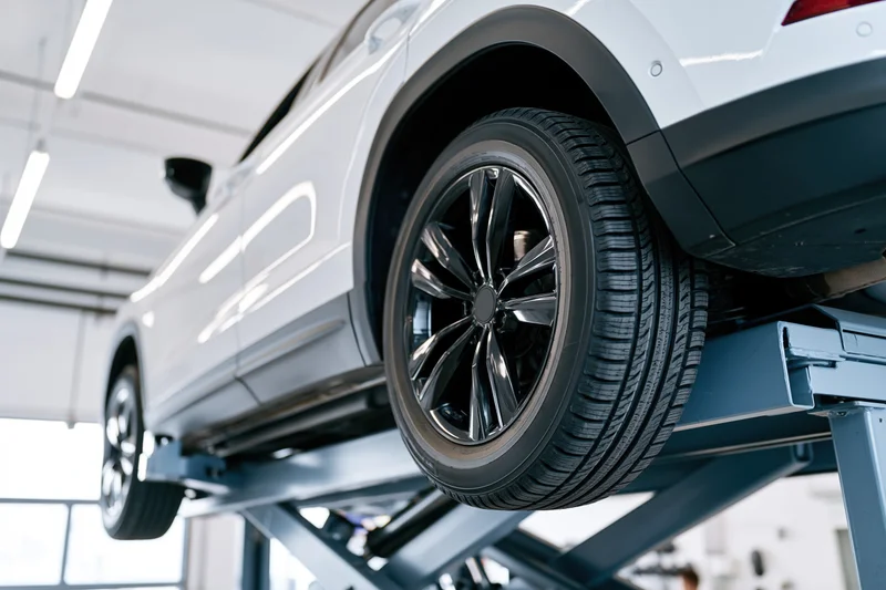 White suv raised on scissor lift in automotive service garage
