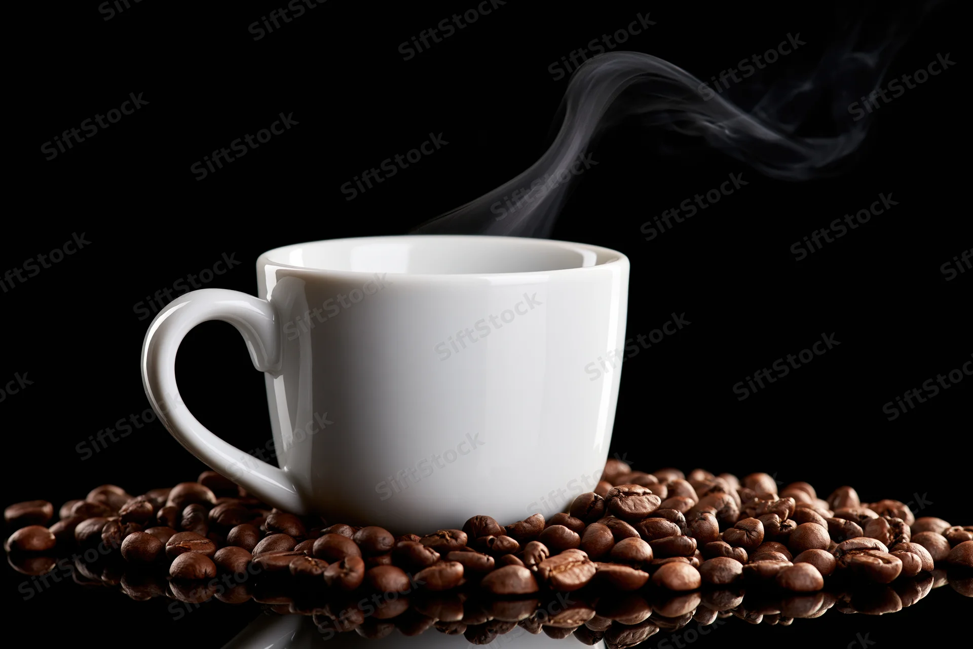 White ceramic coffee cup with rising steam resting on roasted coffee beans on a reflective black surface