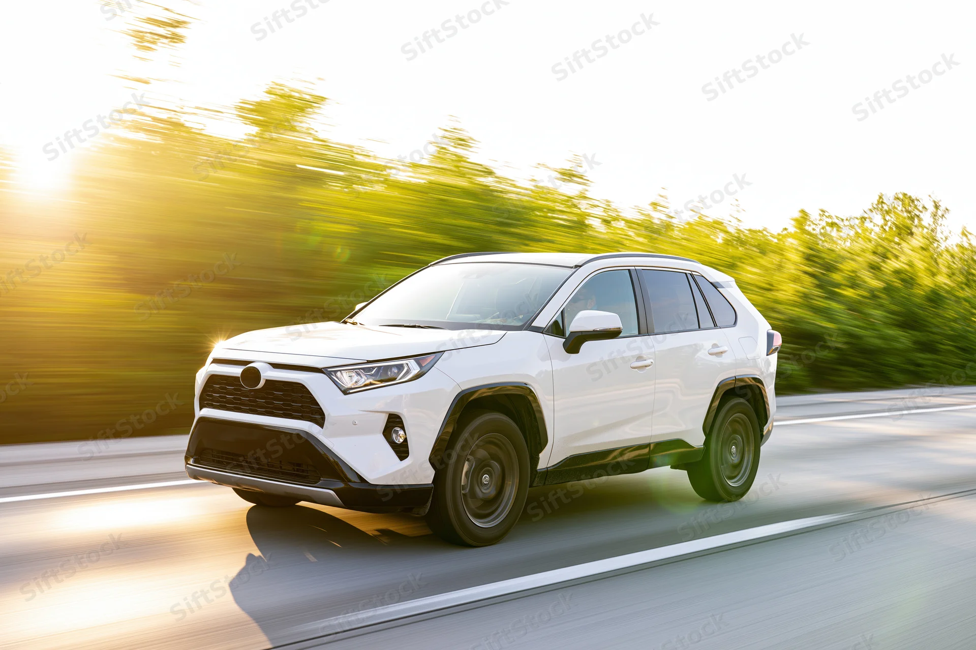 White suv driving on highway at speed, low front angle view