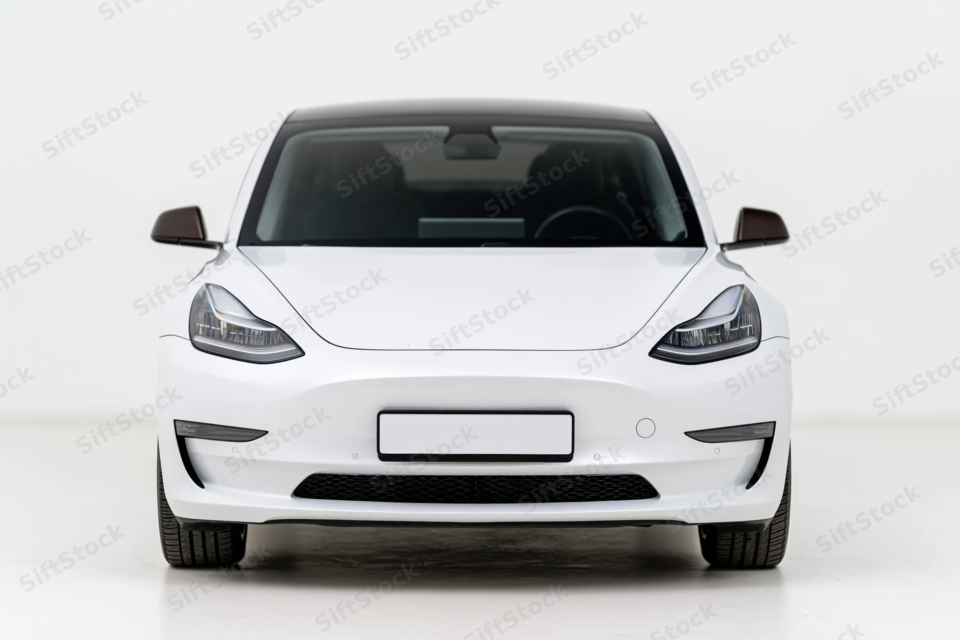 White modern electric sedan viewed straight-on from front in studio setting