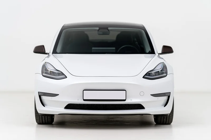 White modern electric sedan viewed straight-on from front in studio setting